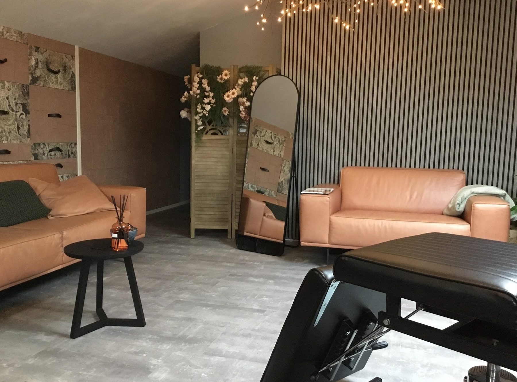 De privé studio van Kim.Inked: perzikkleurige leren banken, een donkere lamellenwand, lichtjes en de tattoostoel