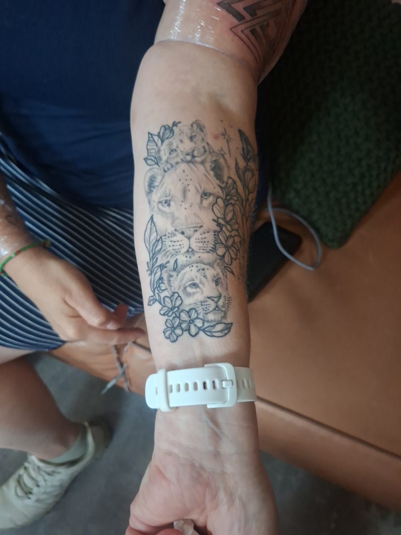Leeuwenkop met bloemen in fineline en dotwork op een onderarm