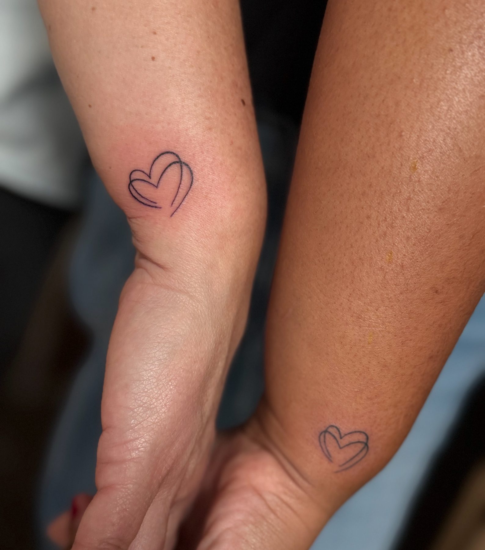 Hetzelfde fijne hartje als matching tattoo op twee onderarmen